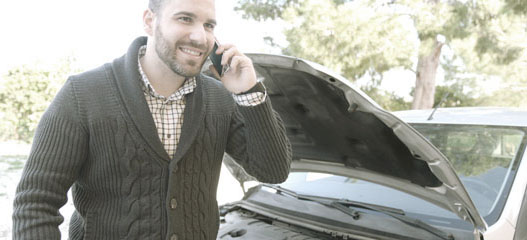hombre con el capó del coche abierto hablando por teléfono