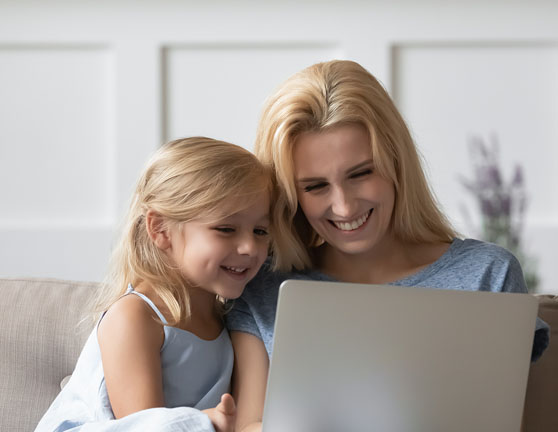 Madre e hija sonriendo mientras visualizan algo en el ordenador