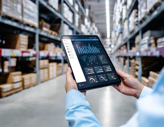 Persona en un almacén sujetando una tablet son gráficos económicos