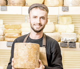 Trabajador con un queso entre las manos en un local comercial