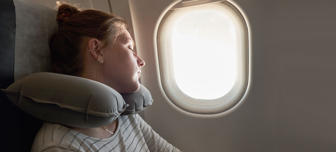 Chica joven durmiendo cerca de la ventana de un avión 